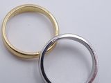 two gold and silver rings on a white surface with a diamond in the middle