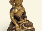 brass statue of a seated buddha with a crown on her head