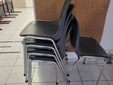 four black chairs in a room with a corkboard on the wall