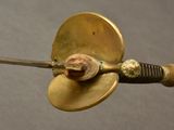 a small brass object with a metal handle on a gray surface