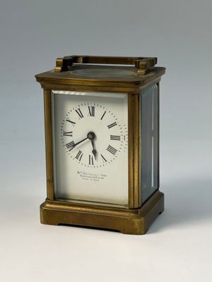 une petite horloge en laiton avec des chiffres romains sur le cadran