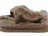 statue of a dog laying down on a plate on a white surface