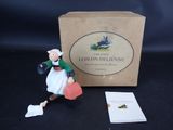 une petite figurine représentant une femme tenant un tuyau d'arrosage à côté d'une boîte