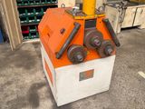 an orange and white machine sitting in a garage next to a pile of boxes