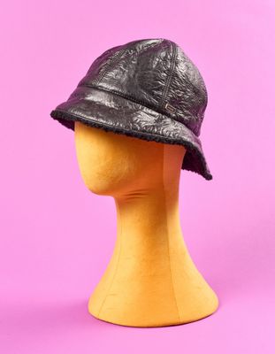 chapeau de pêcheur en cuir noir posé sur une tête de mannequin, sur fond rose