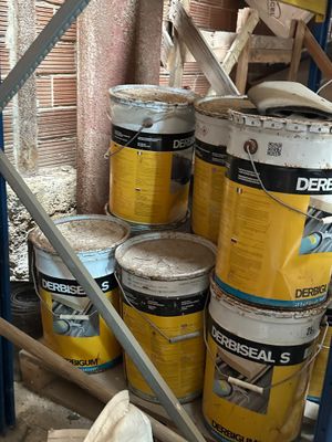 several buckets of paint sitting on a shelf in a room