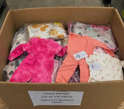 une boîte en carton remplie de vêtements pour bébés, mise en vente dans la rue