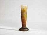 a tall glass vase with a brown base on a white background