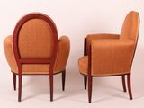 pair of orange upholstered chairs against a white wall