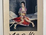 an old photo of a woman in a kimono sitting on a bed