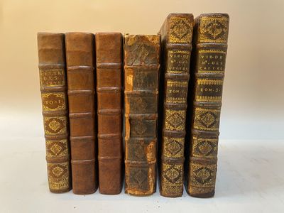 plusieurs vieux livres sont alignés sur une surface blanche