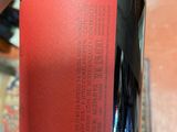someone is holding a bottle of wine with a red label on it