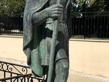 a statue of a man holding a staff in front of a fence