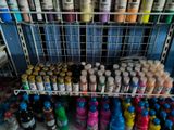 many different colors of paint on the shelves