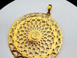 a close up of a gold plated pendant on a white surface