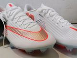 une paire de chaussures de foot blanches et orange posées sur une table