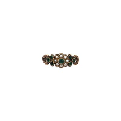 a close up of a ring with green stones and pearls