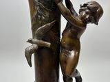 bronze statue of a boy reaching into a vase with a bird on it