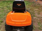 a close up of an orange lawn mower parked in a yard