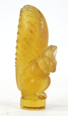 a yellow glass figurine of a squirrel on a white background
