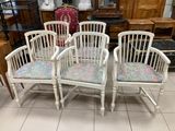 four white chairs with floral upholstered cushions sit in a room