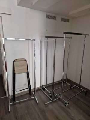 a picture of a room with a rack of clothes and a chair