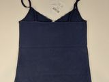 the top of a women ' s blue tank top hanging on a wall