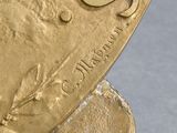 a close up of a gold plate with a bird on it