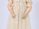 une poupée ancienne en porcelaine représentant une femme en robe blanche