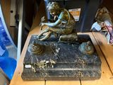 une statue représentant un garçon assis sur un bloc de marbre