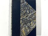 carnet relié en cuir, avec une couverture noire ornée d'un motif en spirale doré et argenté