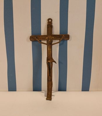 une croix posée sur une table, avec un mur rayé en arrière-plan