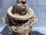 a ceramic vase with a dog on top of it