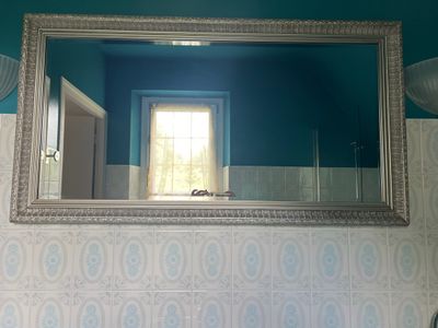 un miroir sur le mur au-dessus d'un lavabo dans une salle de bains