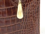 a close up of a brown purse with a gold chain hanging from it