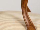 a close up of a wooden chair with a striped cushion