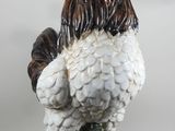 a ceramic rooster that is standing on a green base