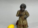 a small figurine of a woman holding a bag next to a lemon