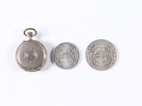 two silver lockes and a silver coin on a white surface