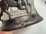 a silver figurine of a man riding a horse on a horse