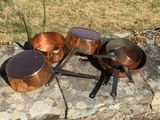 Des casseroles et des poêles sont posées sur une dalle de pierre à l'extérieur