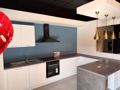une grande cuisine avec un îlot central et un verre à vin posé sur le plan de travail
