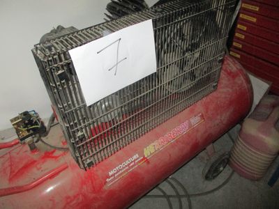 a red air compressor with a sign on top of it