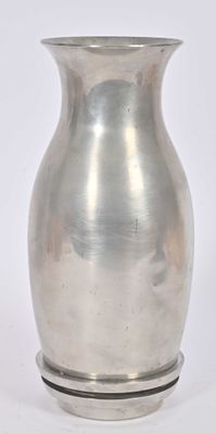 a silver vase that is sitting on a white surface