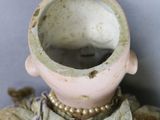 a doll that is sitting on a table with a cup in it