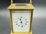 une petite horloge en or dont le cadran est orné de chiffres romains