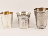 three silver cups sitting next to each other on a white surface
