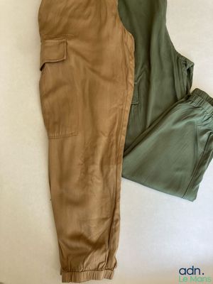 un pantalon posé sur un lit, à côté d'un oreiller
