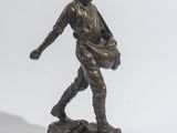 statue en bronze représentant un homme portant un sac, posée sur un socle en marbre