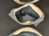 three grey felt pouchs with leather linings on a black surface